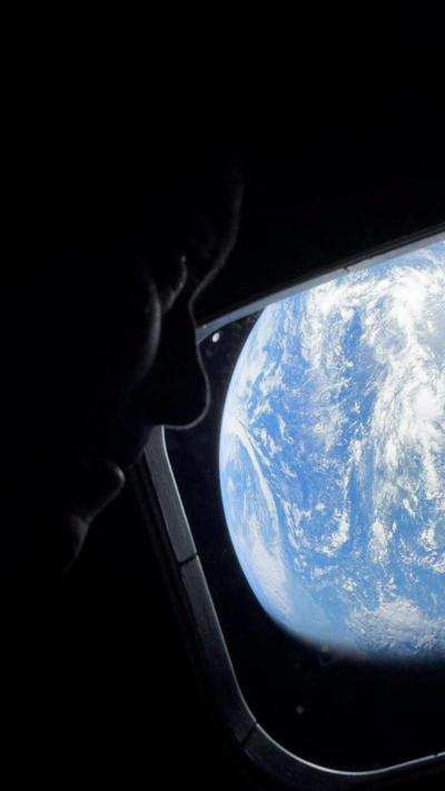 NASA astronaut and Artemis II Commander Reid Wiseman peers out of one of the Orion spacecraft's main cabin windows,