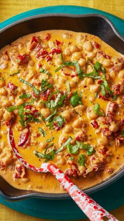 A pan of creamy chickpeas sits on a yellow tablecoth
