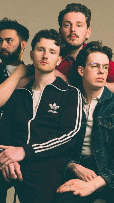 Four male members of a band. Two have beards and one is wearing glasses