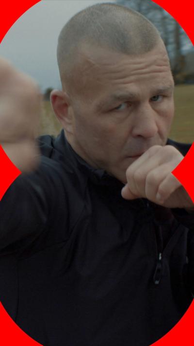 Gary Fox wearing a black tracksuit, throwing a punch towards the camera