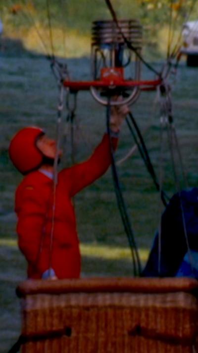 A man in a red jumpsuit in a balloon basket