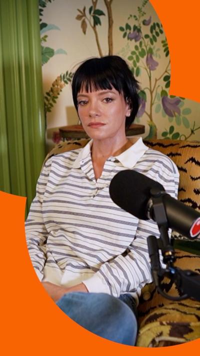 Lily Allen sitting on a sofa with a microphone in front of her
