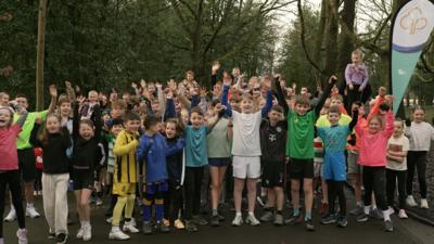A group of children stand with their hands in the air cheering