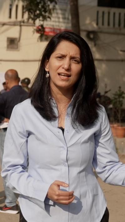 A BBC correspondent speaking to camera wearing a light blue collared shirt