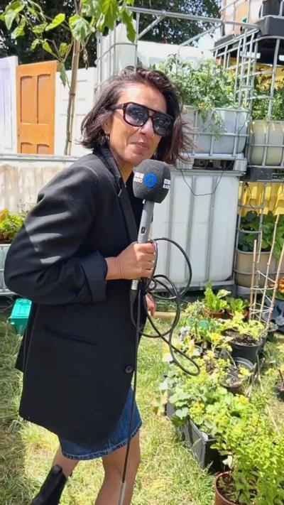Anita Rani walking through an allotment with a microphone