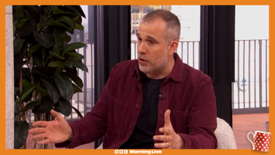 Dr Xand wearing a maroon shacket explains when to worry about pain in your leg