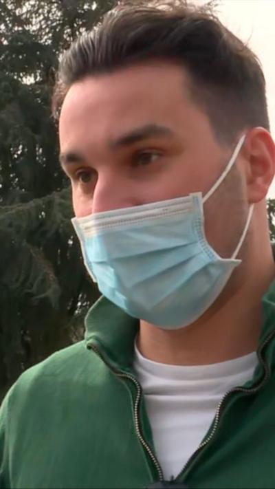 Man wearing face mask, green jumper, white t-shirt 