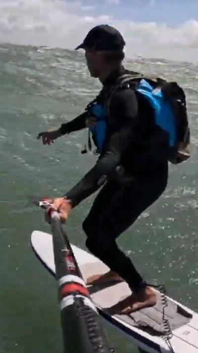 A man in a wet suit on a hydrofoil board.