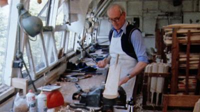 Man in a workshop handmaking a cricket bat. 