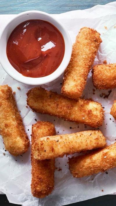 Mozzarella sticks on baking sheet, with a red dip beside.