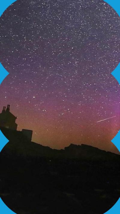 Northern Lights and a meteor over a rural skyline.