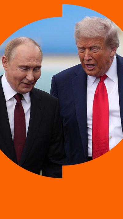 Vladimir Putin and Donald Trump, both in blue suits and red ties, talk as they walk at an airbase in Alaska