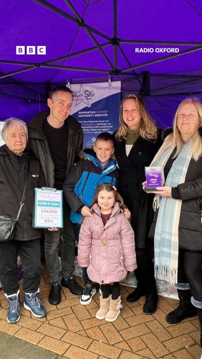 A group of people under a purple tent.