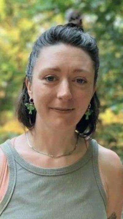 Dr Frances Hopkins - woman wearing a green top, in a wood with black hair in a bun.