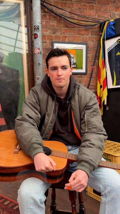 Man with dark hair holding guitar