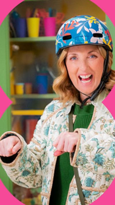 Julie Wilson Nimmo is smiling. She wears a bike helmet and holds her fists up as if she is riding a bike.