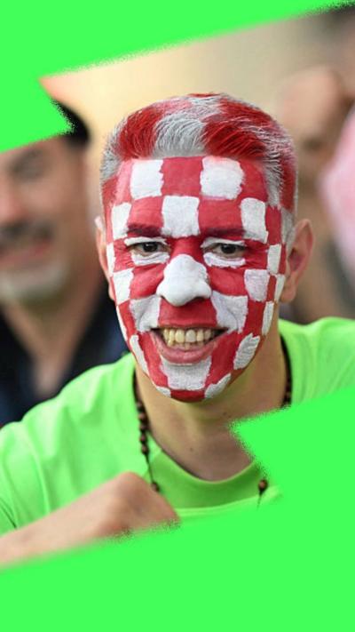 Croatian football fan with red and white squares painted on his face smiling at camera