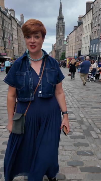 Woman in blue dress and top on a cobbled street with church in background