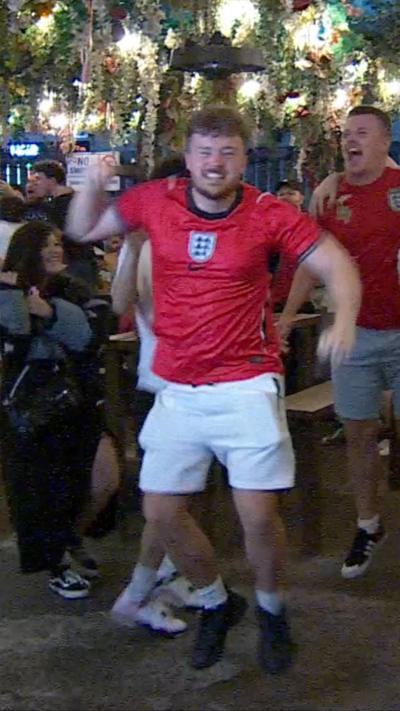 An England fan wearing a red shirt celebrating Harry Kane's match winning penalty.