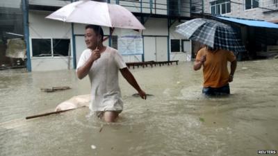 People wade through a flooded street at a town hit by Typhoon Soudelor in Ningde, Fujian province, China