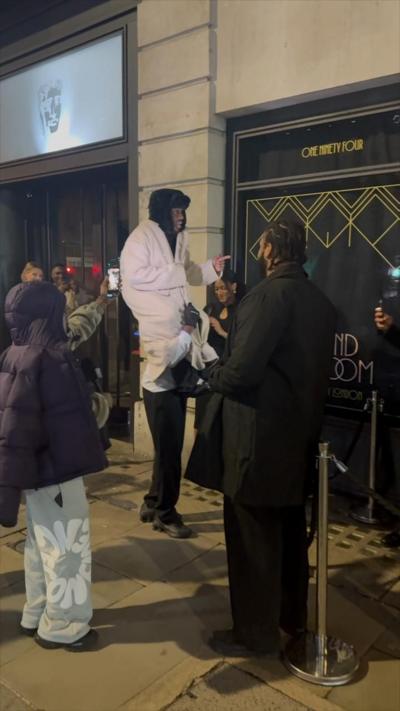 A man sits on the shoulders of another man to appear taller.