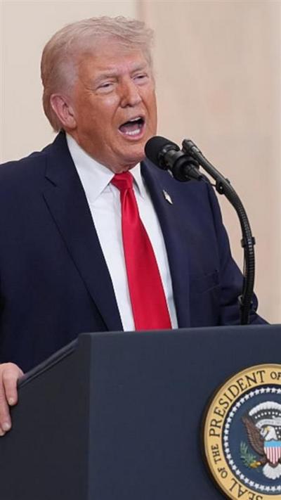 Donald Trump wears a blue suit, red tie and American flag pin as he speaks into a microphone in an address to the nation.