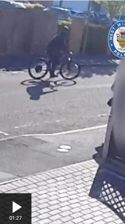 CCTV still shows a person dressed in black on a bike in the street. the image is blurry and their face is covered by a balaclava. There is a West Midlands Police logo in the corner.