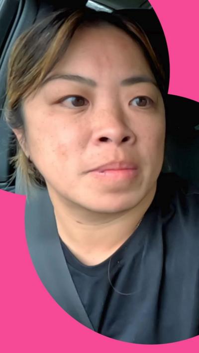 Meea is sat in the drivers seat of a car next to a colleague holding a camera.