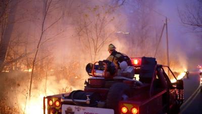 Firefighter crew drives down street with burning trees