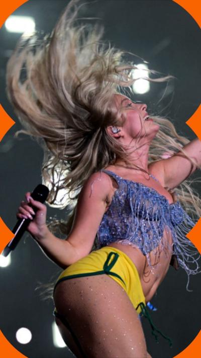 Zara Larsson on stage flipping her long blonde hair in the air. She holds a mic in one hand and the other is raised up