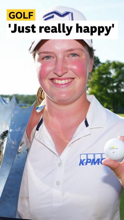 Lottie Woads smiles and holds up silver trophy 