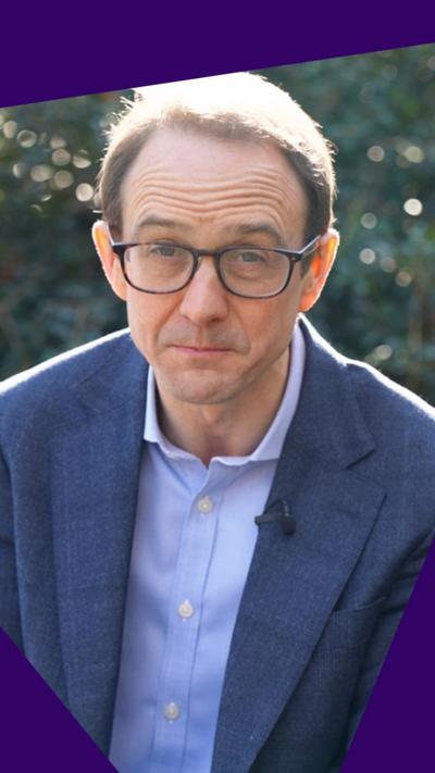 A close up shot of BBC political editor Chris Mason, wearing dark glasses, a blue shirt and blazer