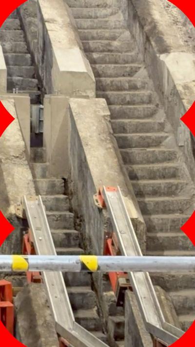 Concrete stairs can be seen beneath escalators at a Tube station.