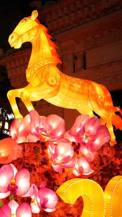 Yellow horse lantern lit up in bright yellow over pink flower lanterns