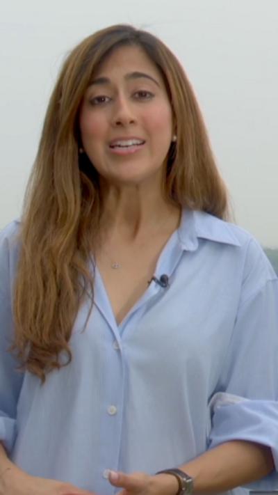 A woman with long brown hair wearing a light blue shirt.