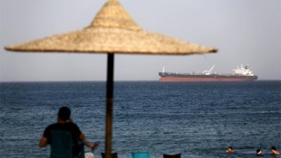Enjoying the beach while an Egyptian tanker steams past heading for the Suez Canal