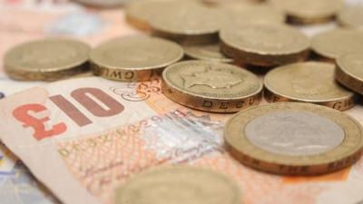 A selection of one pound coins, two pound coins and bank notes