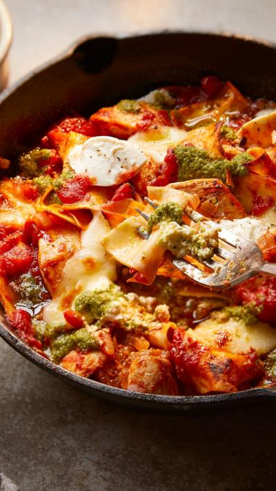 A one handled pan with chicken lasagne in. A hand holding a fork can also be seen.
© BBC