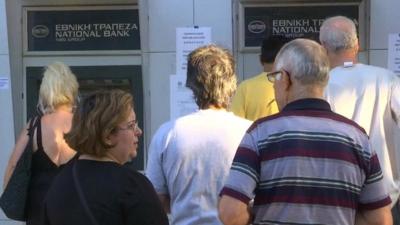 People wait at a bank's cash machines in Greece