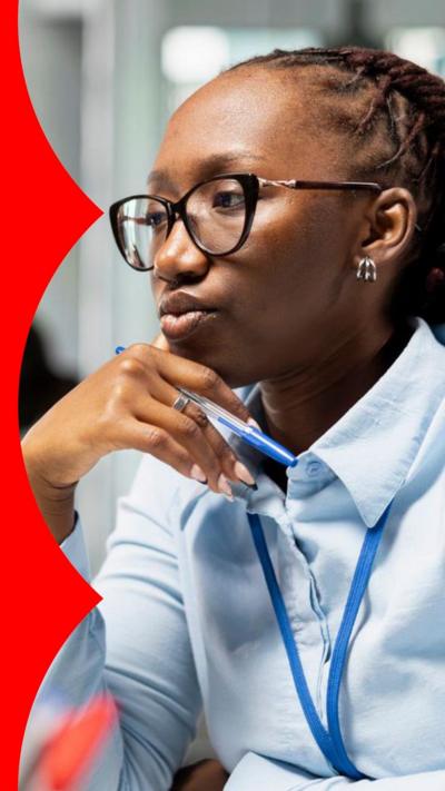 A woman wearing glasses and a blue shirt looks at a computer screen out of shot