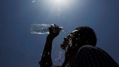 A man pours water on his face during a hot day in India.