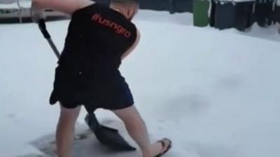 Man in shorts clearing snow