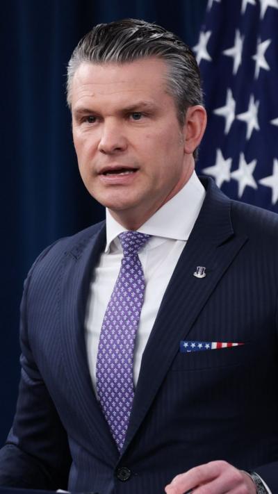 Pete Hegseth in a blue suit and purple patterned tie