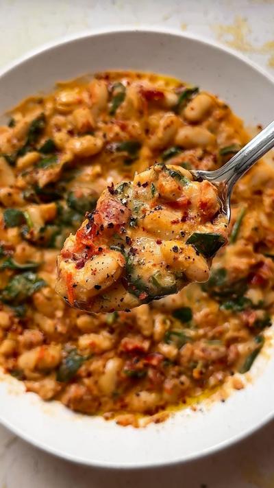 Creamy sun-dried tomato beans on a silver spoon.