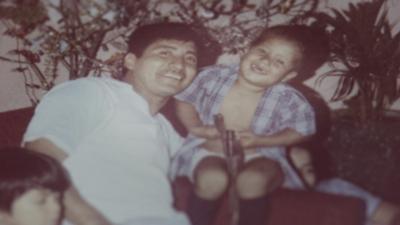 A young Guatemalan boy and man sit smiling on a sofa