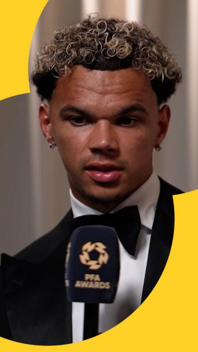 Nico O'Reilly in a tuxedo, holding a PFA-branded microphone