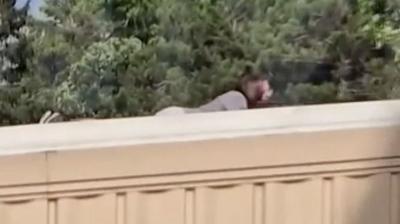 Man lying down on roof holding weapon