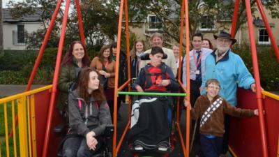 Children around a new wheelchair swing