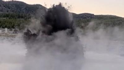 A dark mass of murky water erupts into the sky from the Black Diamond Pool in Yellowstone Park.