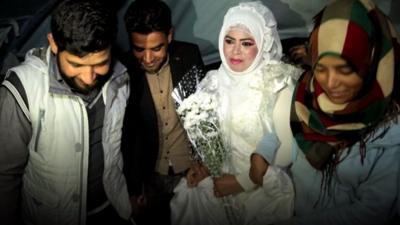 Syrian woman wearing wedding dress surrounded by husband to be and friends